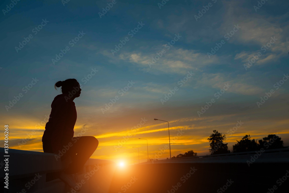 silhouette woman on road watching yellow and orange setting sun at sunset silhouette woman on road watching yellow and orange setting sun at sunset