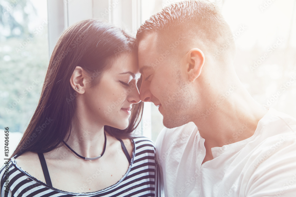 Portrait of beautiful romantic young couple man woman in love hugging, kissing, indoors at home, toned with filters, authentic lifestyle Portrait of beautiful romantic young couple man woman in love hugging, kissing, indoors at home, toned with filters, authentic lifestyle