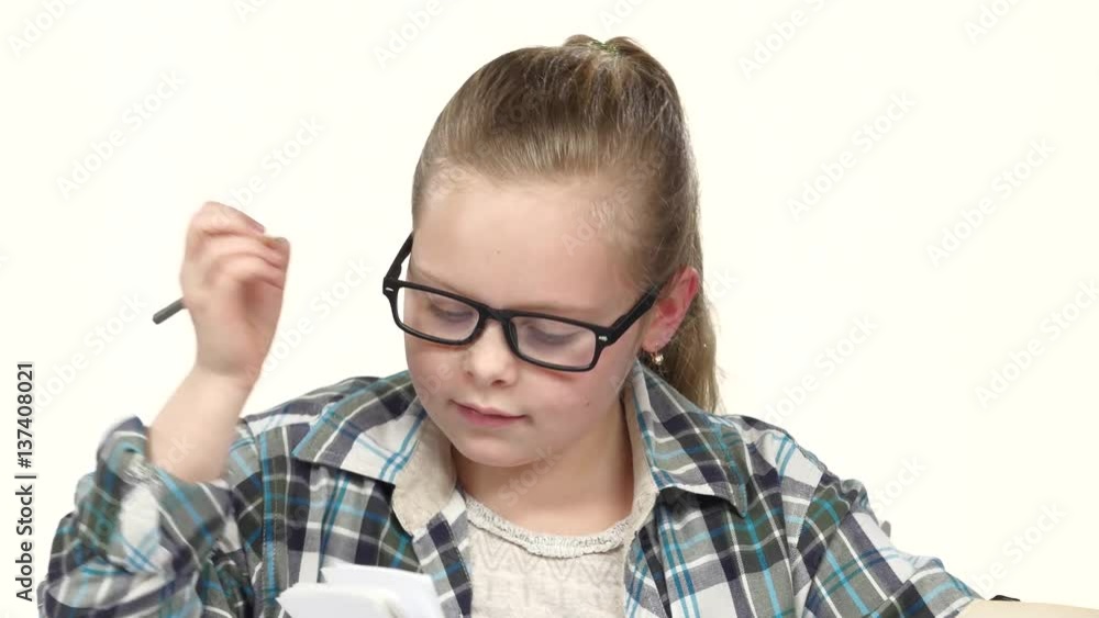 Girl carefully read and write data to the notebook. White background. Close up Girl carefully read and write data to the notebook. White background. Close up