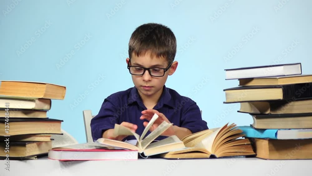 Little boy reading a different book. Blue background. Slow motion Little boy reading a different book. Blue background. Slow motion