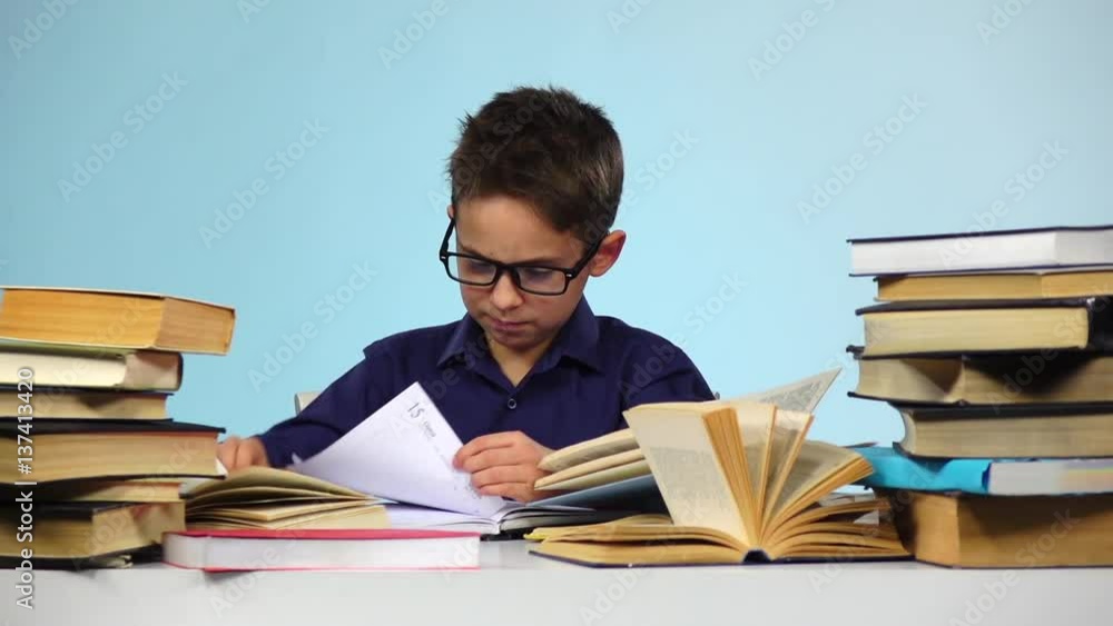 Little boy pulls out sheets of books. Blue background. Slow motion Little boy pulls out sheets of books. Blue background. Slow motion