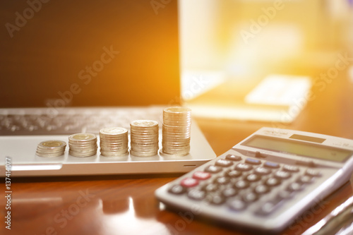 Concept business finance save money, Coins stack on wood table with blurred calculator background , stack of money, rows of coins for finance and banking concept, selective focus