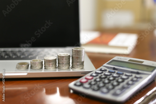 Concept business finance save money, Coins stack on wood table with blurred calculator background , stack of money, rows of coins for finance and banking concept, selective focus