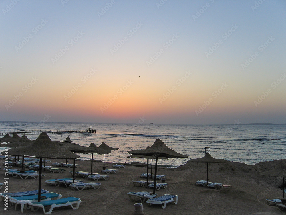 Red Sea in Egypt during sunrise with blue water and beach with umbrellas and chairs
