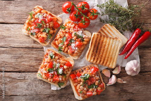Tasty sandwich with white beans, tomatoes, cheese and herbs closeup. horizontal top view