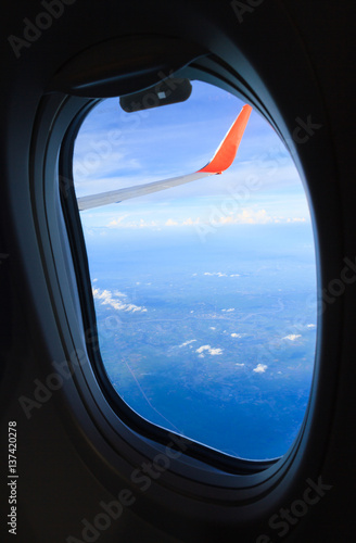 Cloudscape view of window at flying airplane.