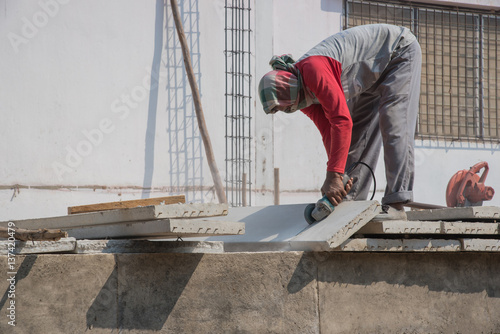 Builder worker with grinder machine cutting concreate floor at construction site