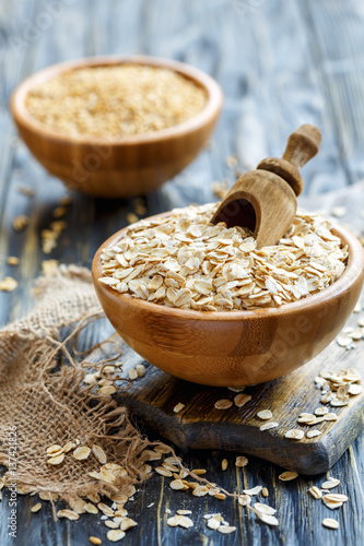 Bowl with oat flakes and wooden scoop.