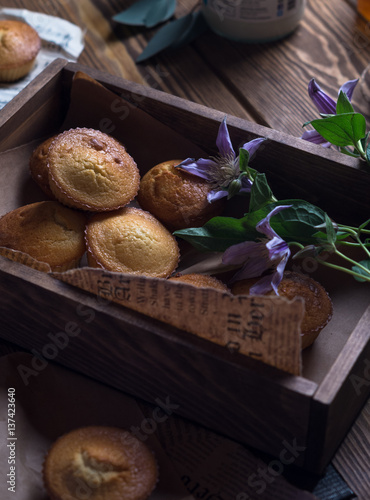 Muffins with honey, coconut puree in a wooden box with flowers, paper, teapot on a brown wooden table
