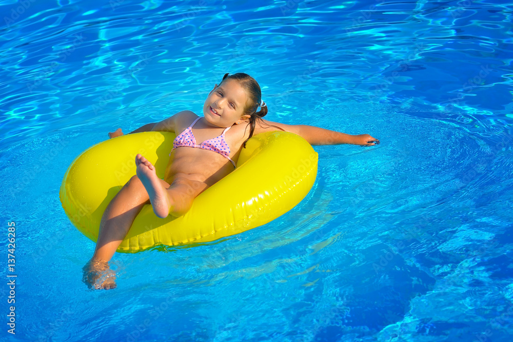 Real toddler girl relaxing at swimming pool