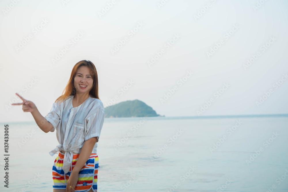 Happy woman standing arms outstretched  and enjoy life on the beach at Sea