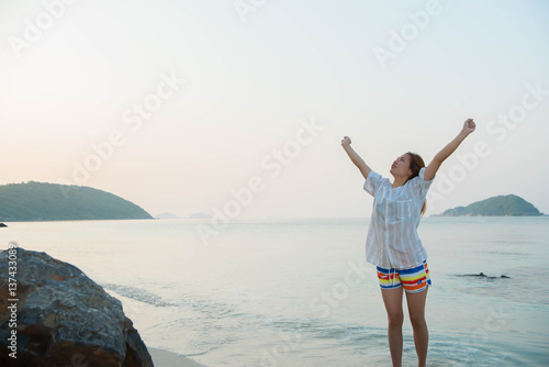 Happy woman standing arms outstretched and enjoy life on the beach at Sea