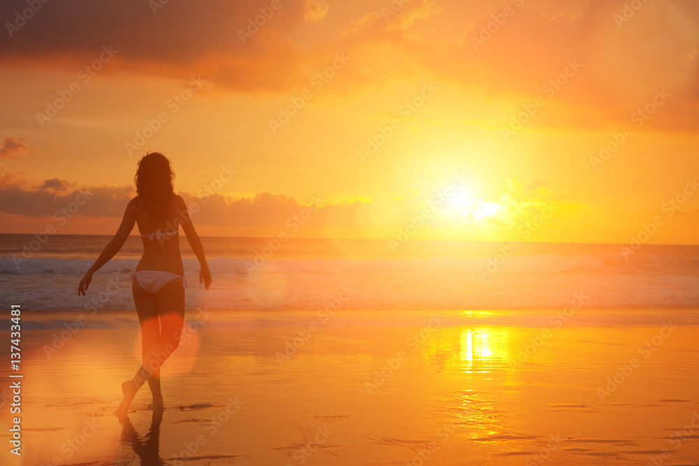 Silhouette of woman on the sunset. Colorful dawn over the sea. Nature beauty. Carefree woman enjoying the sunset on the beach. Happy lifestyle