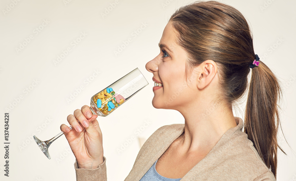 Smiling woman drinking vitamins pills from vine glass. Smiling woman drinking vitamins pills from vine glass.