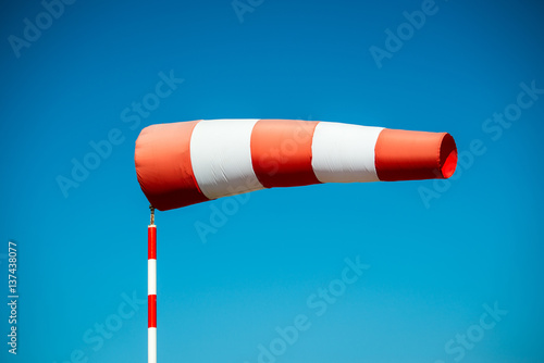 Horizontally flying windsock (wind vane) with blue sky in the background.