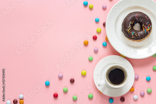Chocolate donut with a cup of coffee on a pink background. Space for text.