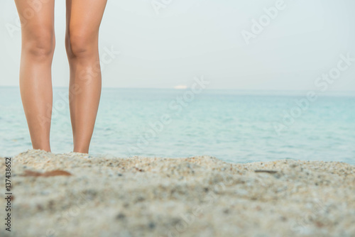 Woman legs on the sand beach and sea water.
