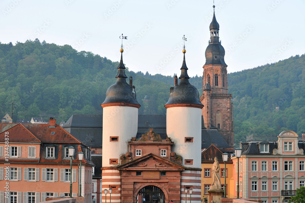Obraz premium Heidelberg z mostową bramą Heiliggeistkirche i postacią Karla Theodora w porannym słońcu