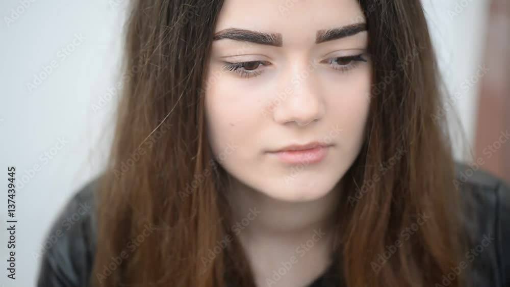 The girl with long hair and brown eyes raises his eyes and looks into the camera. The girl with long hair and brown eyes raises his eyes and looks into the camera.