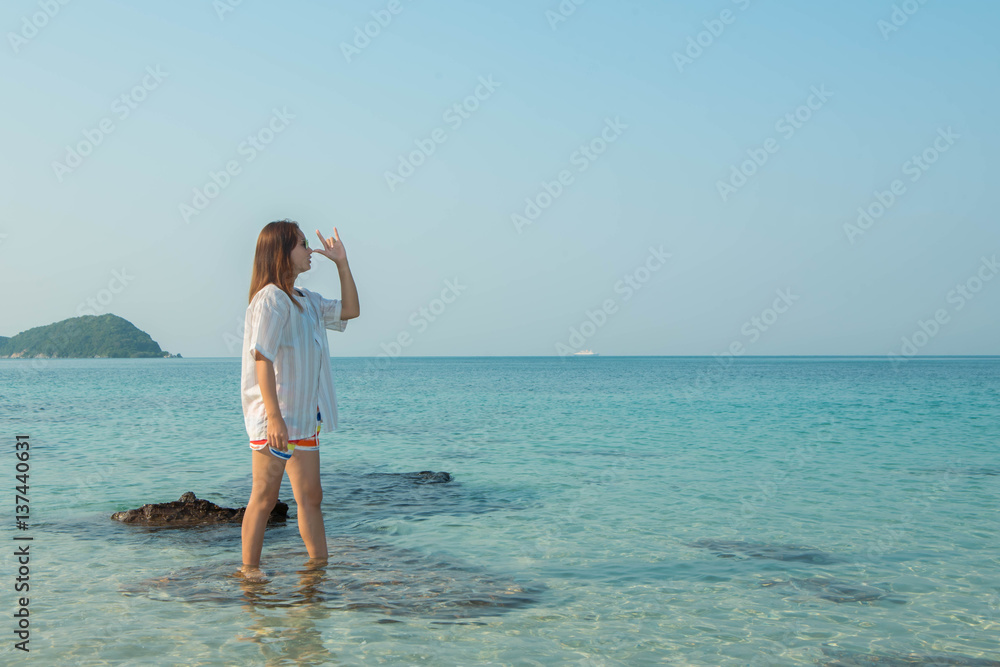 Happy woman standing arms outstretched on the beach at Sea Happy woman standing arms outstretched on the beach at Sea