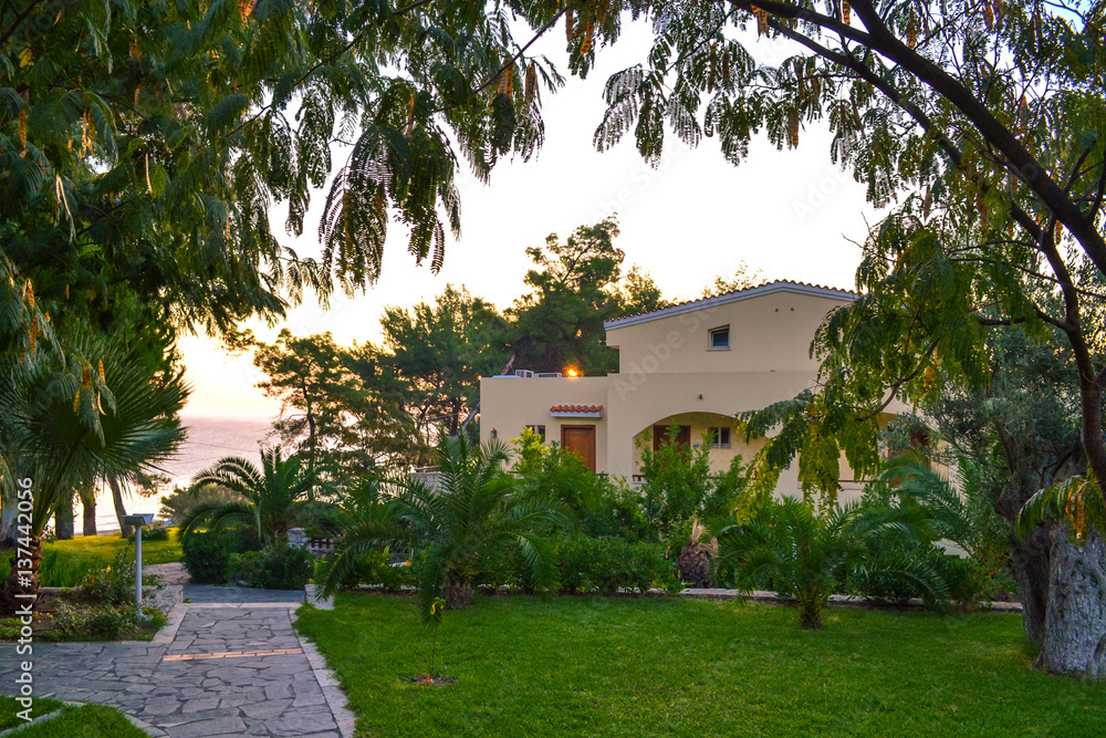 Fototapeta premium The house by the sea among green plants. Greek hotel Aegean Melathron, Greece - September, 2013.