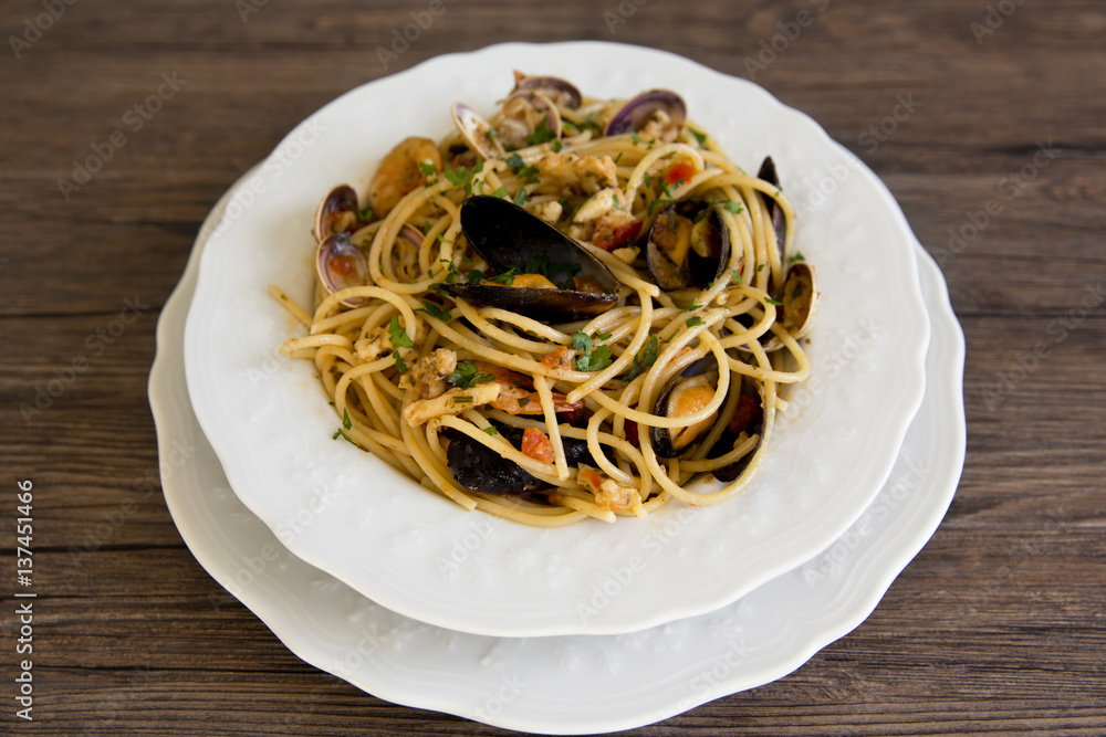 Spaghetti with seafood in white ceramic plate on wooden background Spaghetti with seafood in white ceramic plate on wooden background
