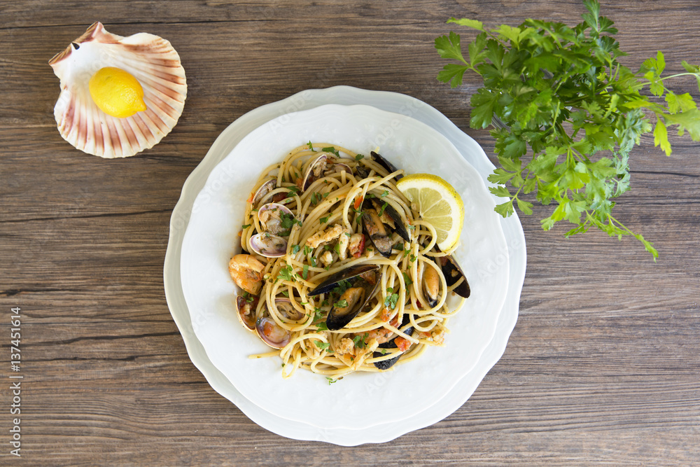 Spaghetti with seafood in white ceramic plate on wooden background Spaghetti with seafood in white ceramic plate on wooden background