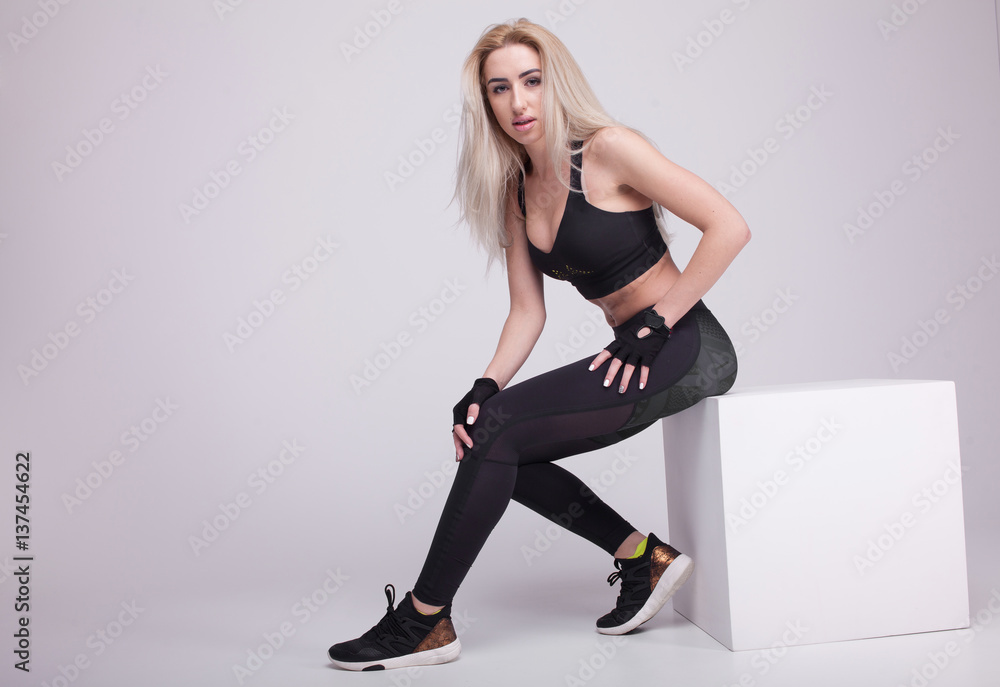 Caucasian female athlete sitting on a box. Fit young woman taking break after her workout at gym. Caucasian female athlete sitting on a box. Fit young woman taking break after her workout at gym.