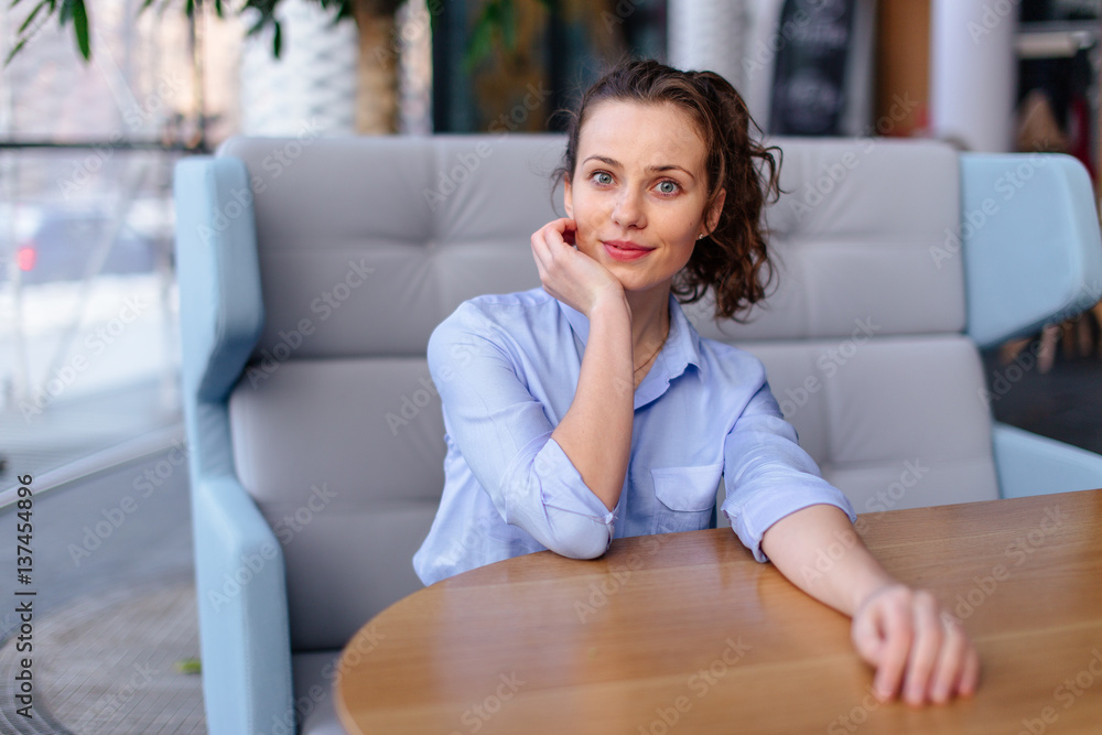 Pretty girl sitting on the bench in cafe place and looking forward Pretty girl sitting on the bench in cafe place and looking forward