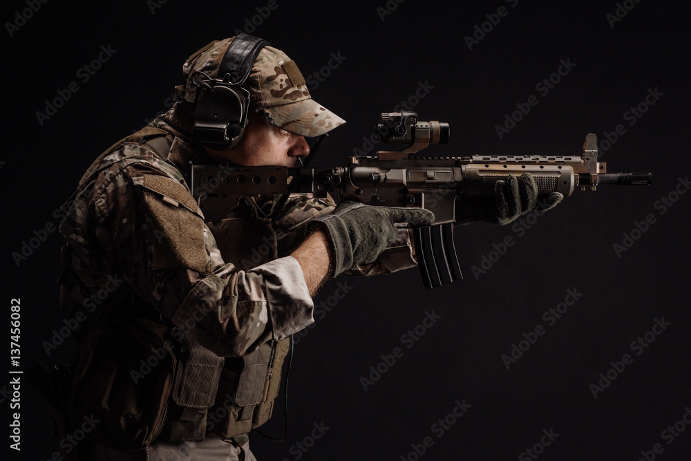 Portrait soldier or private military contractor holding sniper rifle. war, army, weapon, technology and people concept. Image on a black background. Portrait soldier or private military contractor holding sniper rifle. war, army, weapon, technology and people concept. Image on a black background.