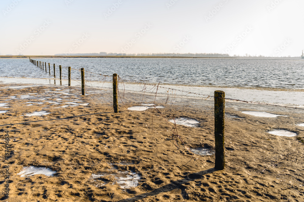 Fence of wooden poles and barbed wire in a flooded area
