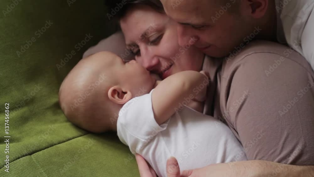mom and dad playing with his baby son on the bed. Happy family concept mom and dad playing with his baby son on the bed. Happy family concept