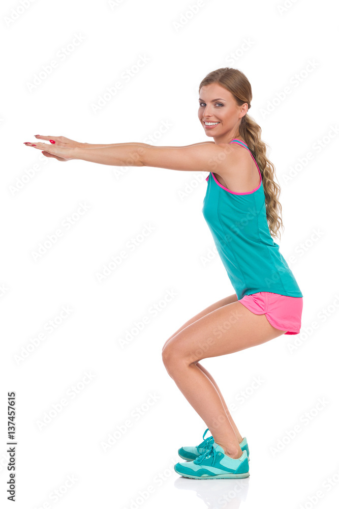 Smiling Woman Does A Squat. Side View Smiling Woman Does A Squat. Side View