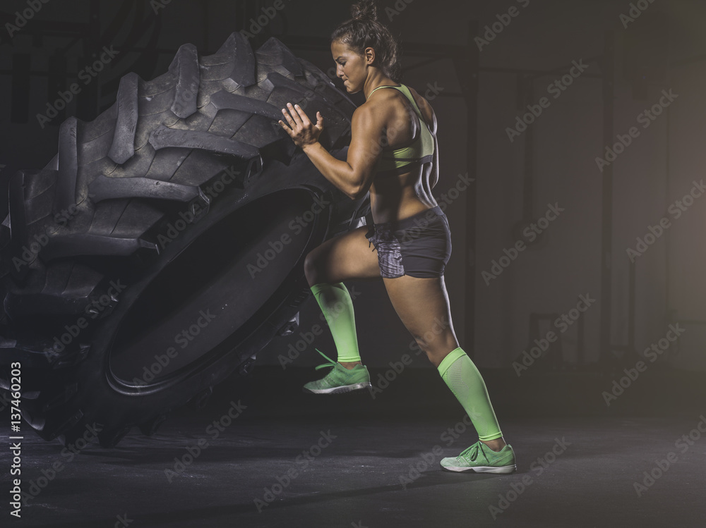 Young woman lifting up a tractor tire Young woman lifting up a tractor tire