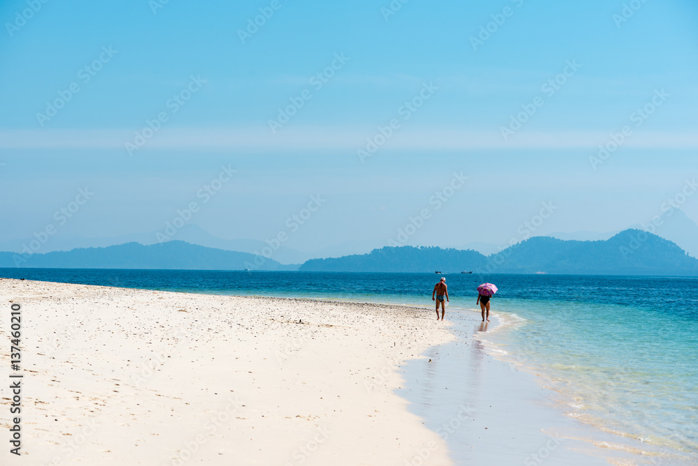 Elderly couple walking on a white sand beach