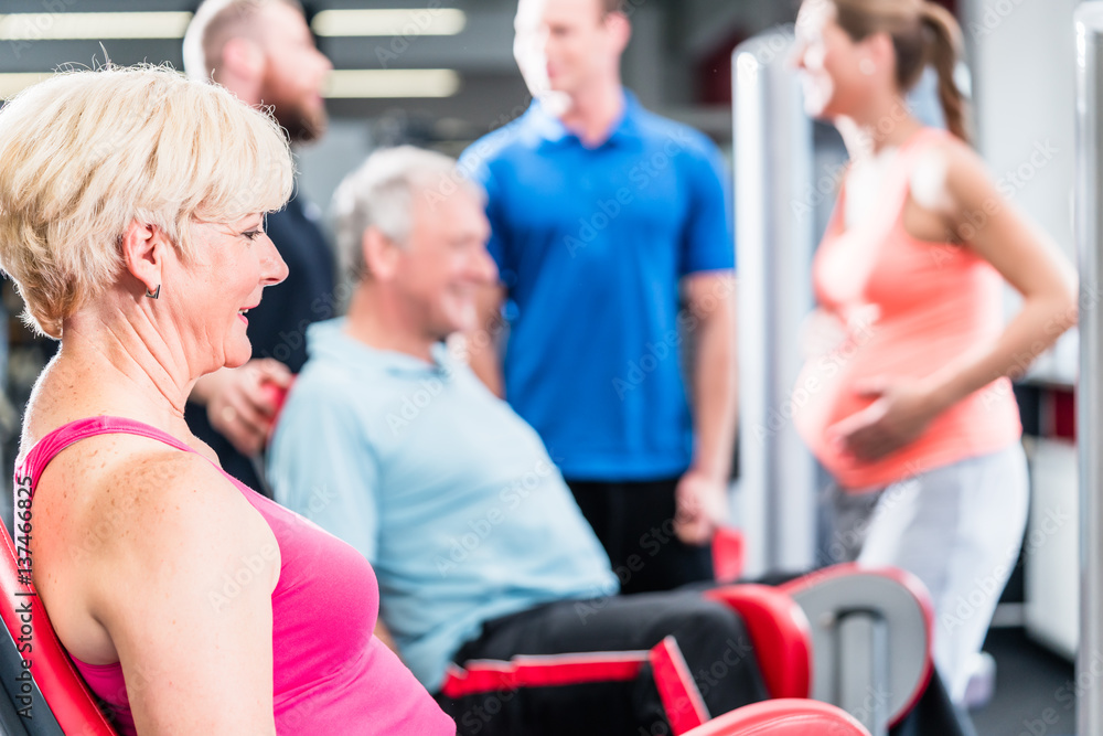 senior woman in group with pregnant woman working out at the gym