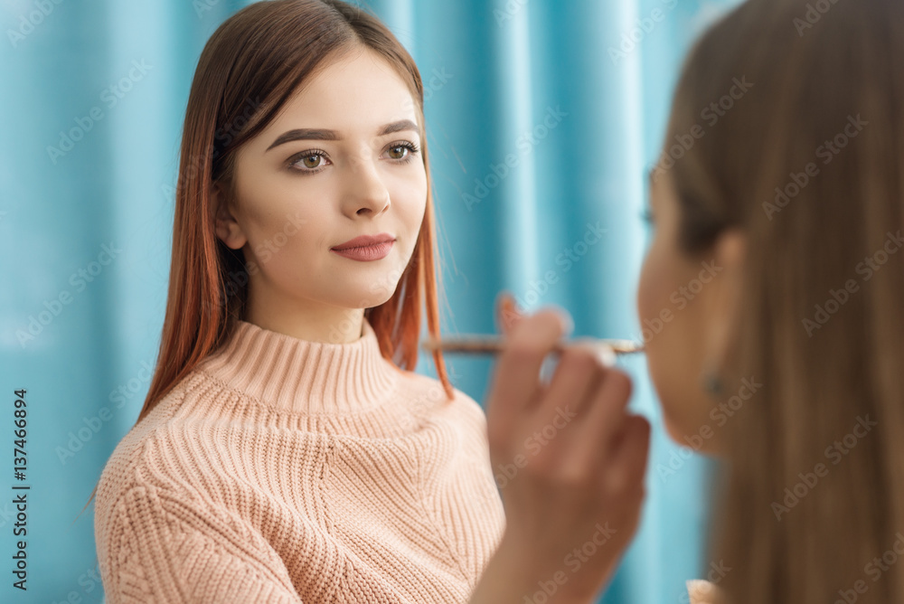 stylist applying makeup on woman's face in beauty salon stylist applying makeup on woman's face in beauty salon