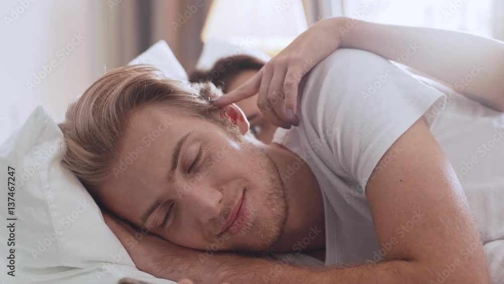 Young Caucasian female flirts with handsome male lying in upset in the morning in bed in slowmotion Young Caucasian female flirts with handsome male lying in upset in the morning in bed in slowmotion