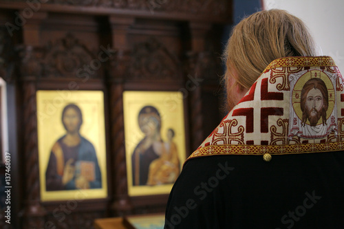  Orthodox bishop praying in front of altar icons photo