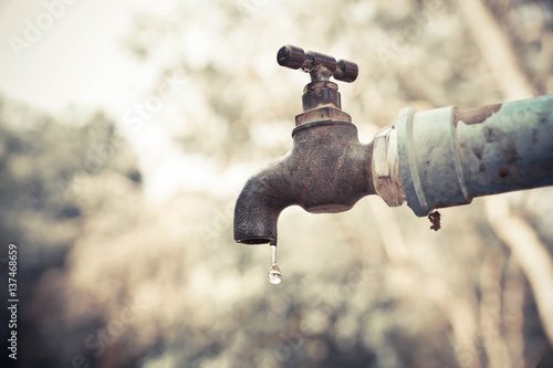 Obraz na płótnie A faucet with a water drop / Water consumption concept