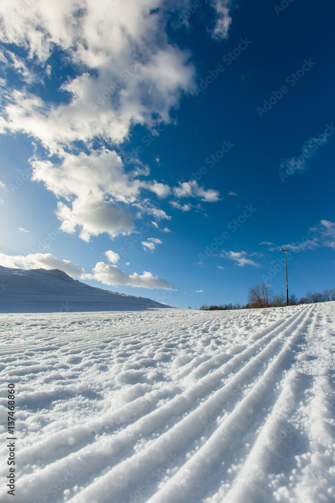Unbroken ski slope, sun and blue sky