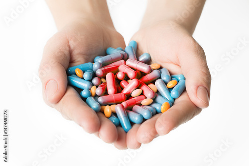 Capsuled blue pills of red pain in man hands