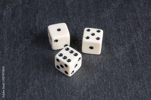small dice on dark stone background 