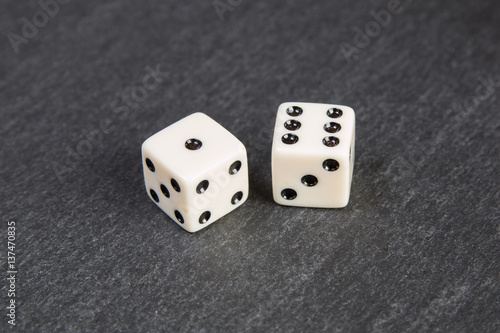 small dice on dark stone background 