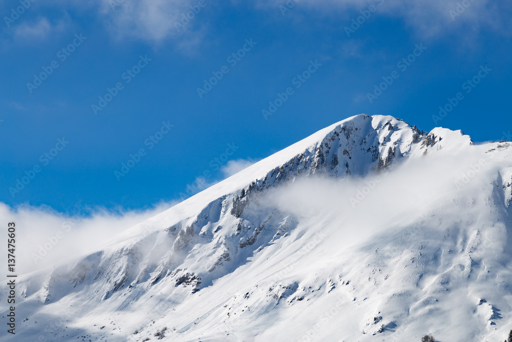 Mountain top covered in snow and clouds