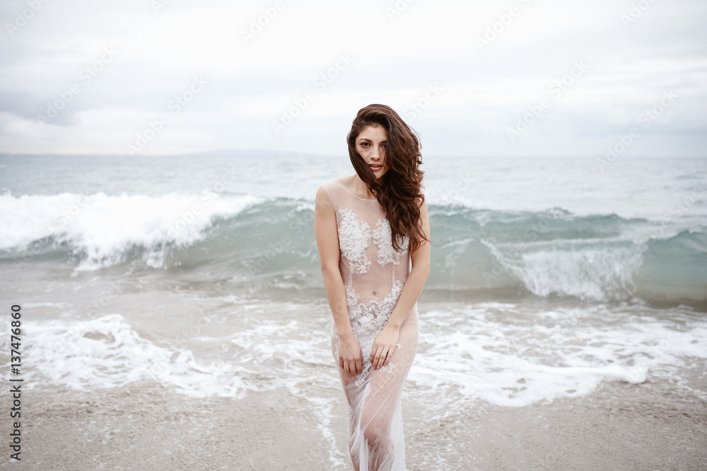 Portrait of a beautiful young woman standing on the beach against sea Portrait of a beautiful young woman standing on the beach against sea