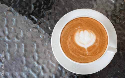 Top view of hot coffee latte art flowershape foam on glass table background photo