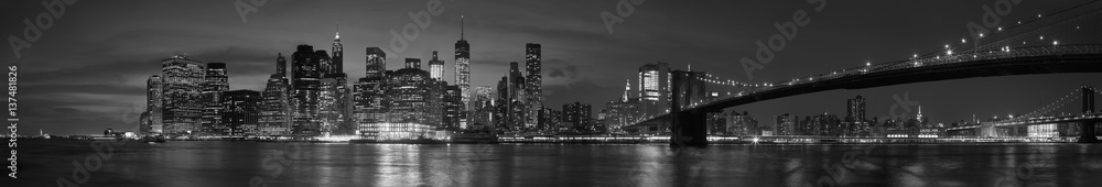 New York city with Brooklyn Bridge, iconic skyline panorama at night in black and white