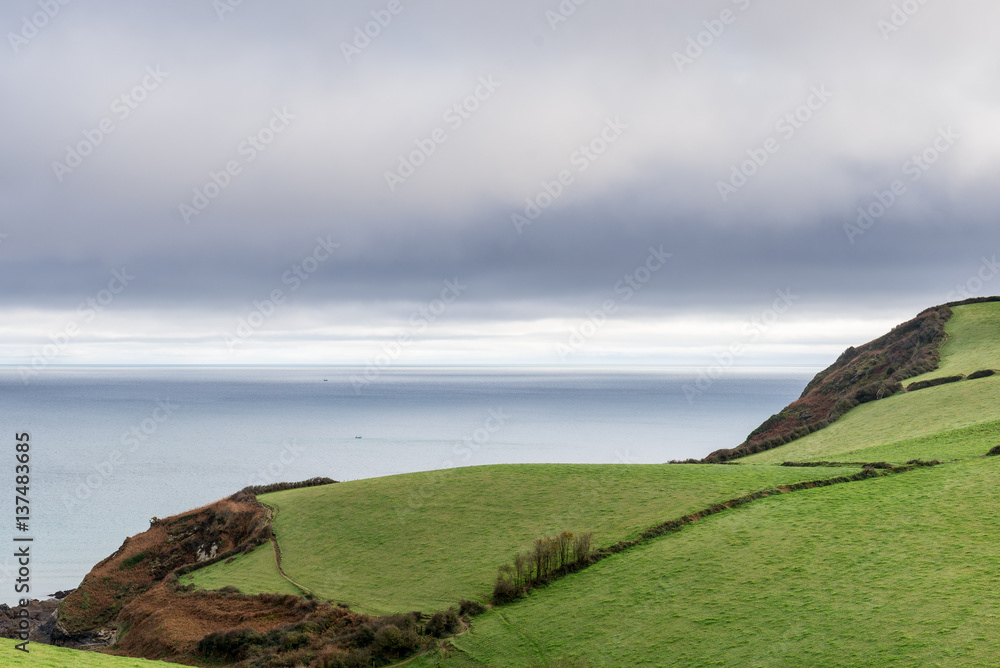 Rolling hills leading to an expanse of sea, under overcast sky