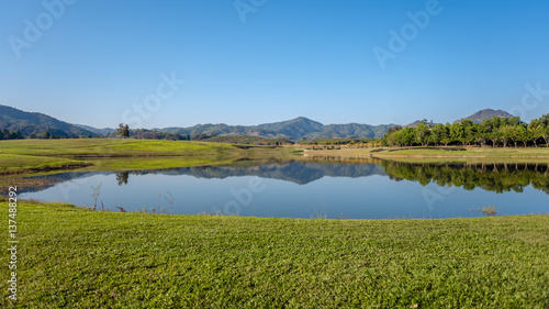 Beautiful lawn and water reflection lake and clear blue sky background.